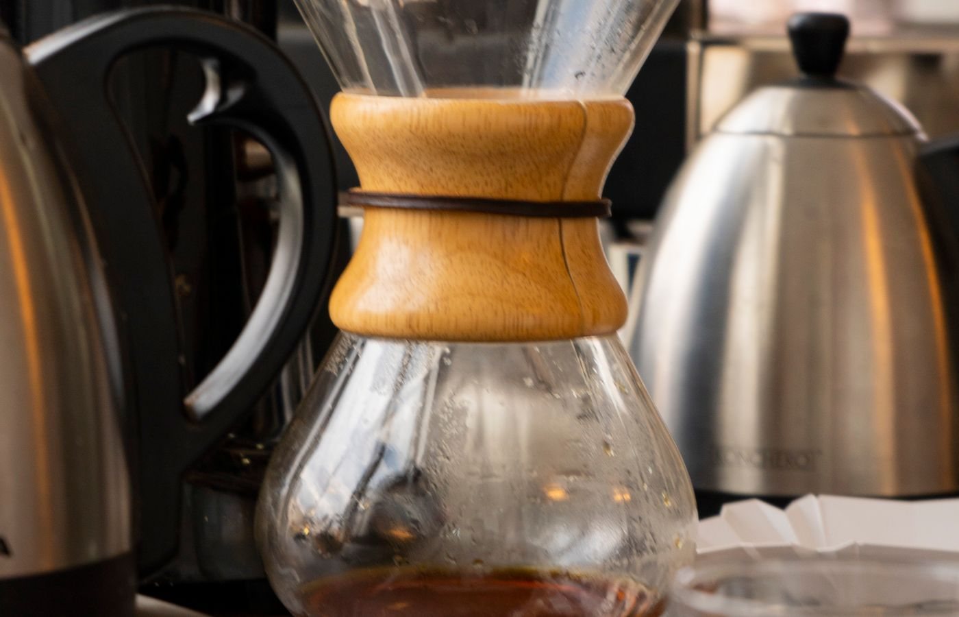 An hourglass pour-over brewer and a kettle on the roastery bench